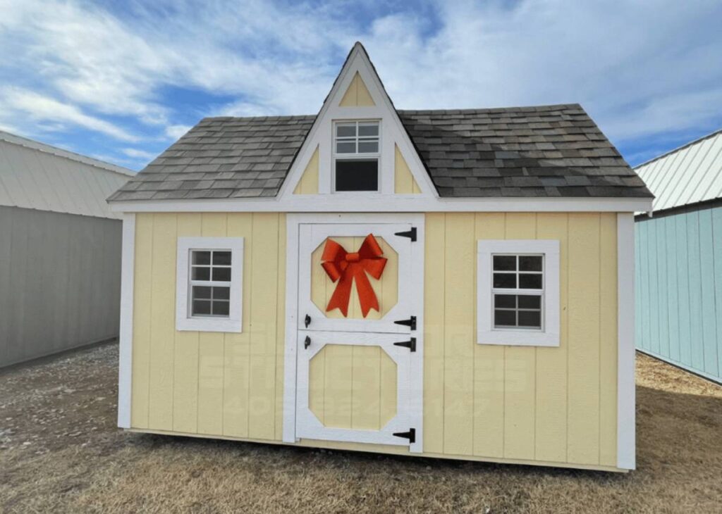Yellow child's wooden playhouse with red bow at Tiny Hive in Giddings, TX